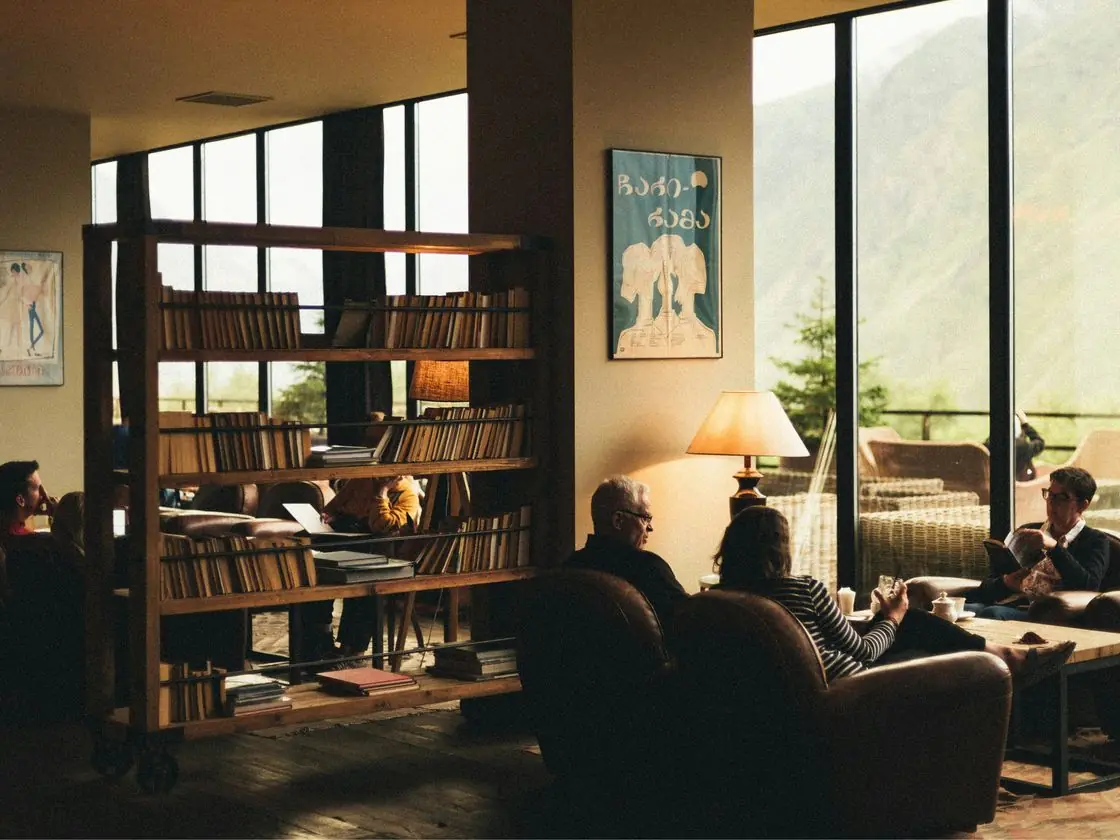 Clients talk in a lounge with bookshelves and large windows