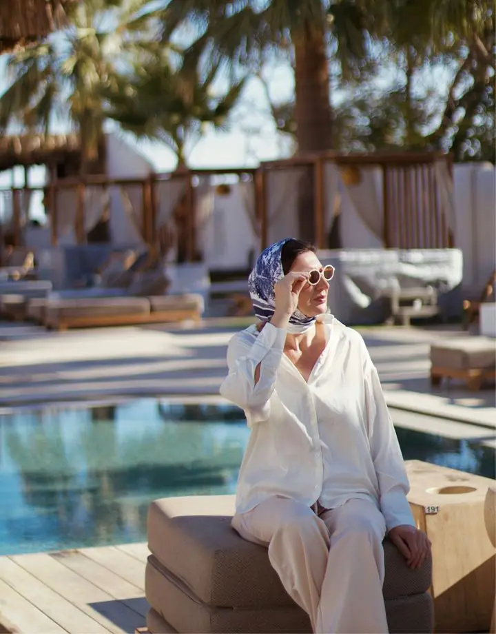 Woman in a headscarf and sunglasses by a resort pool