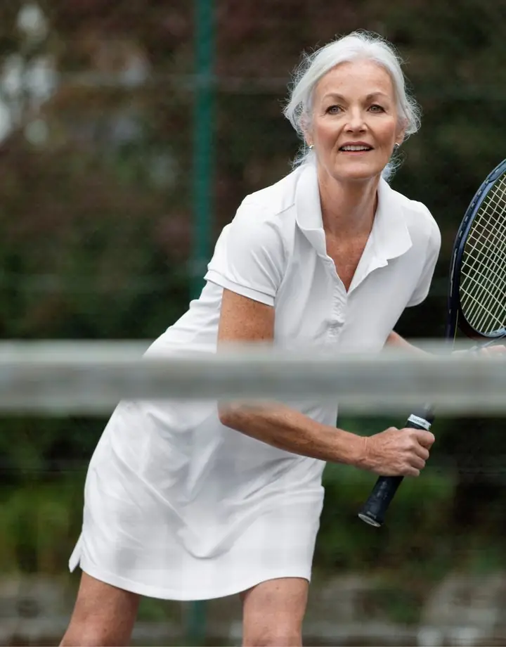 White-haired woman playing tennis