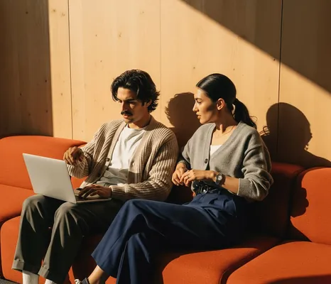Couple sitting on an orange sofa looking at a laptop together